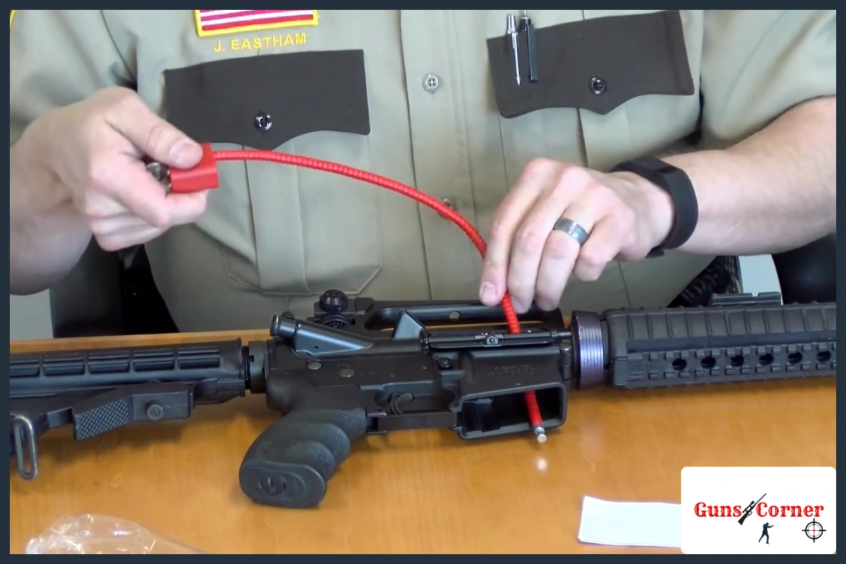 Sheriff deputy threading a red cable gun lock through the open action and magazine well of an unloaded semi-automatic rifle
