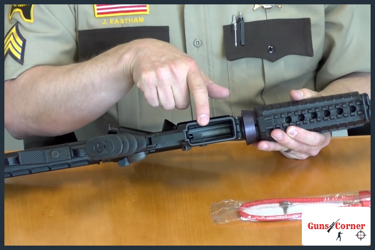 Sheriff deputy pointing to the open action of an unloaded rifle beside a free cable gun lock still in its package